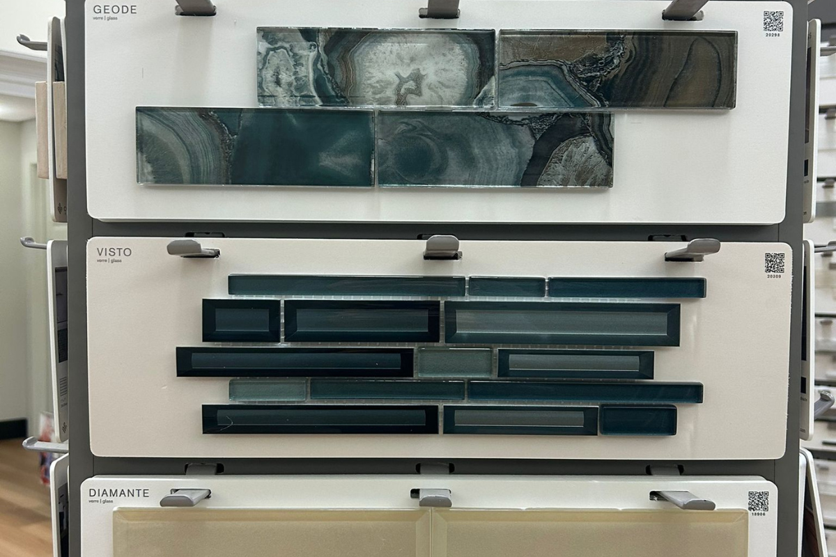 Three rows of tile samples are displayed. The top row, labeled GEODE, shows two rectangular tiles with a marbled, agate-like pattern in shades of blue-green and white. The middle row, labeled VISTO, features a mosaic of rectangular tiles in various shades of blue and teal, arranged in a staggered pattern. The bottom row, labeled DIAMANTE, displays several light beige glass tiles.